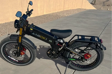 Aniioki A9 Pro Max black electric bike parked on an outdoor concrete driveway, addressing questions like is it safe to charge e bike battery overnight with its secure built-in system.