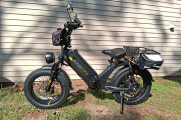 A space grey Aniioki AQ177 48V long-range electric bike with fat tires and a rear cargo rack parked outdoors in a suburban yard