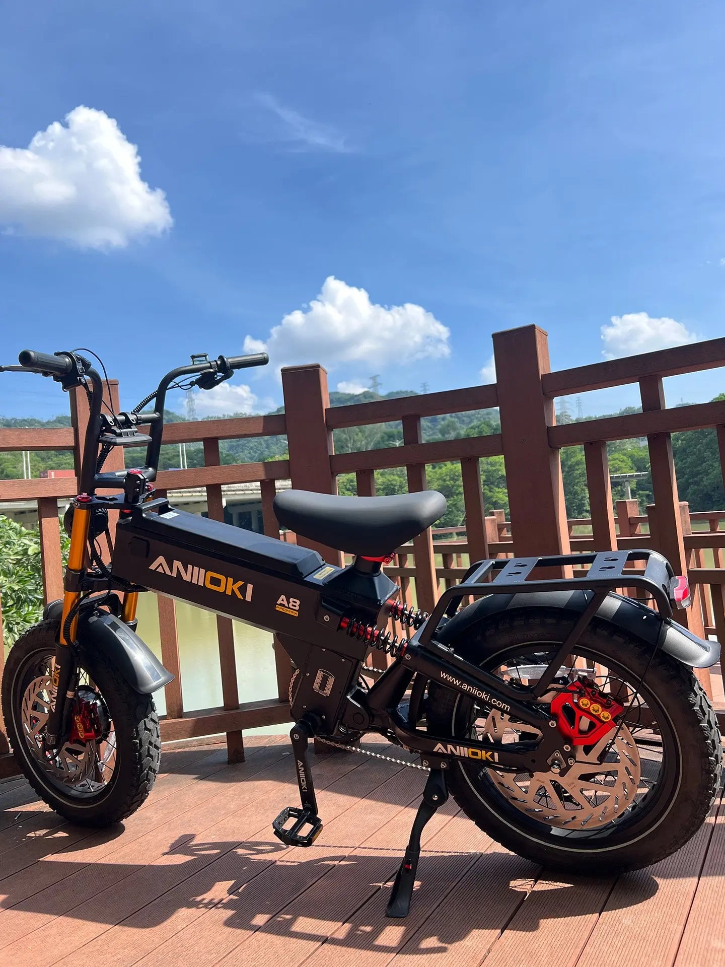 A close-up side profile of the black Aniioki A8 Pro Max 52V dual motor ebike on a scenic wooden deck, highlighting its high torque electric bike power (230 N.m Max Torque) and heavy-duty frame