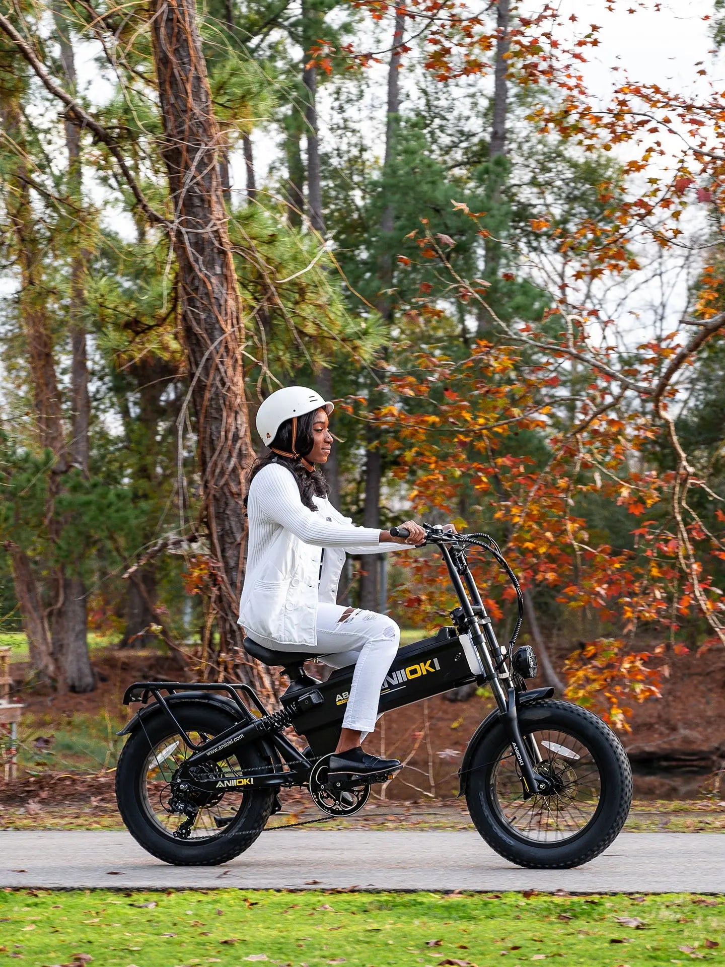 An African American woman riding Aniioki A8 Pro Max single motor ebike on a scenic paved trail, showcasing its comfortable upright riding position.