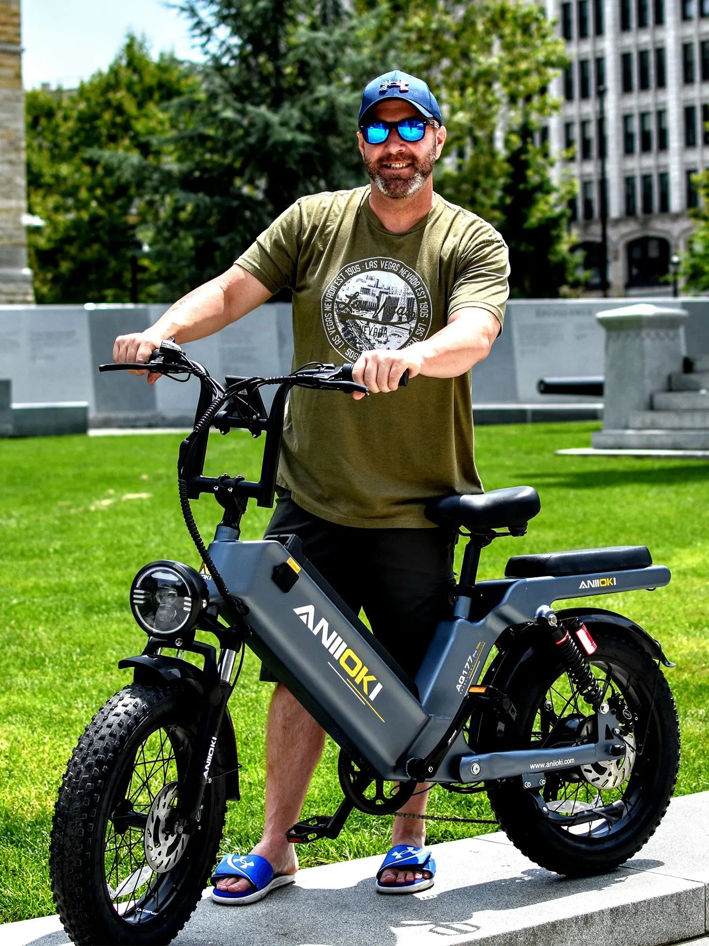 A man standing with a grey Aniioki AQ177 Pro Max 48V, featuring a powerful 1200W motor, recognized as an affordable 1200w ebike for daily commuting.