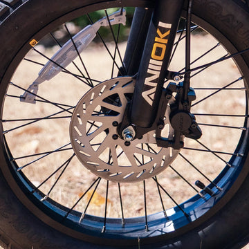 Front disc brake system and suspension fork detail on the Aniioki AQ177 60V electric bike, featuring heavy-duty rotors and spoked wheels for reliable stopping power.
